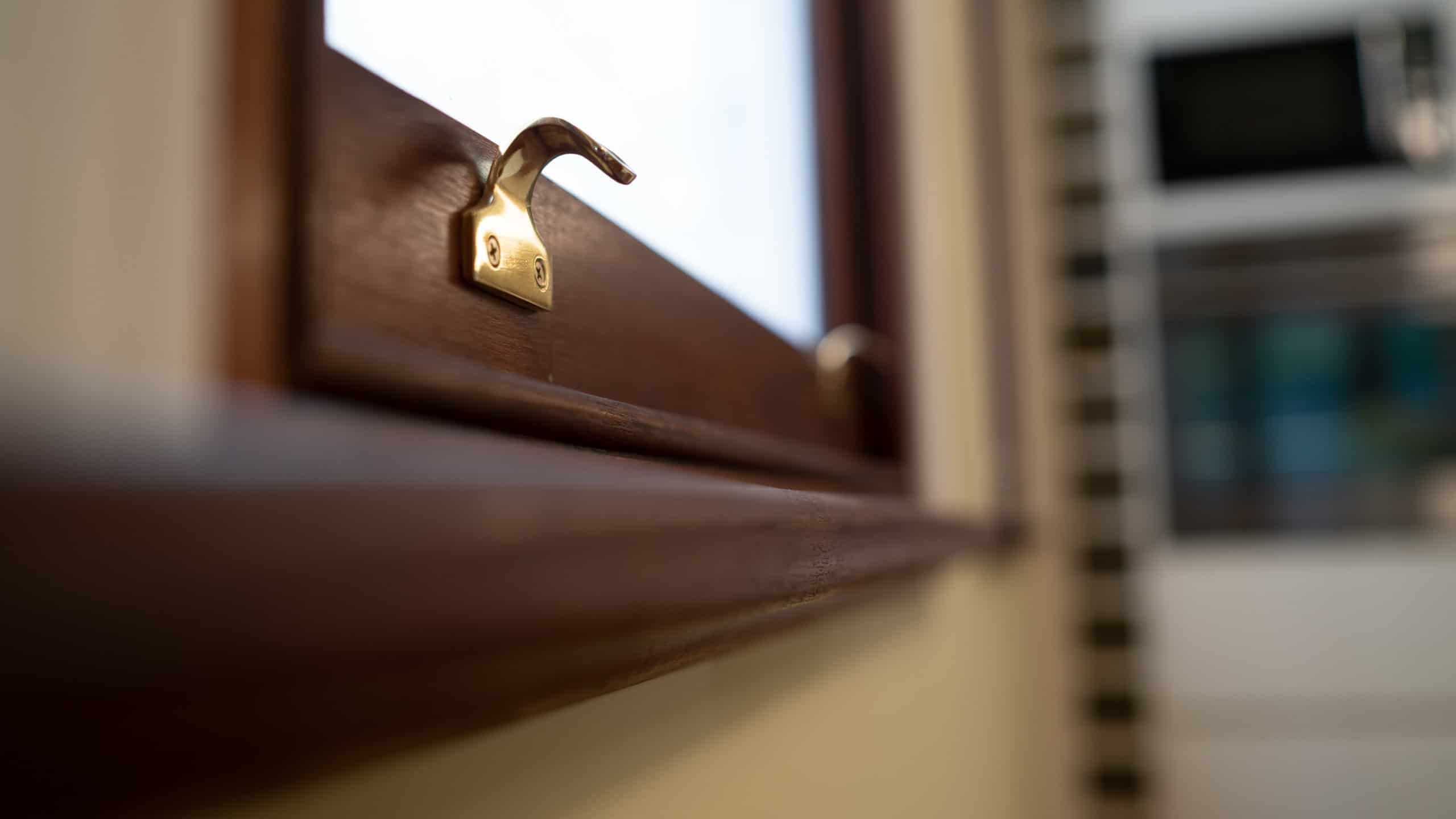 Close up picture of a wooden window frame & sill with brass handles